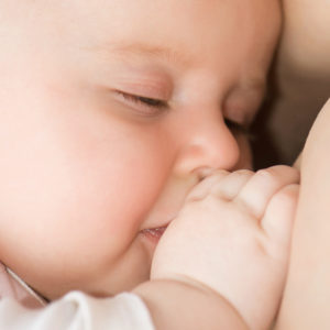 Mother breast feeding her baby with closed eyes